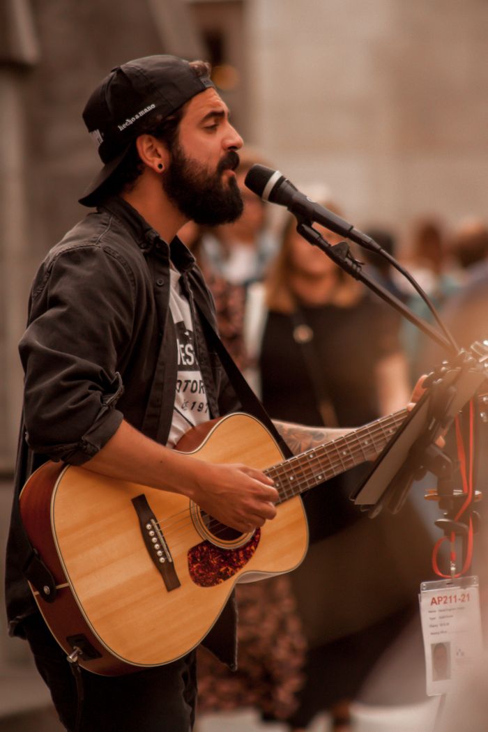 A bearded musician singing and playing guitar on a Dublin street.