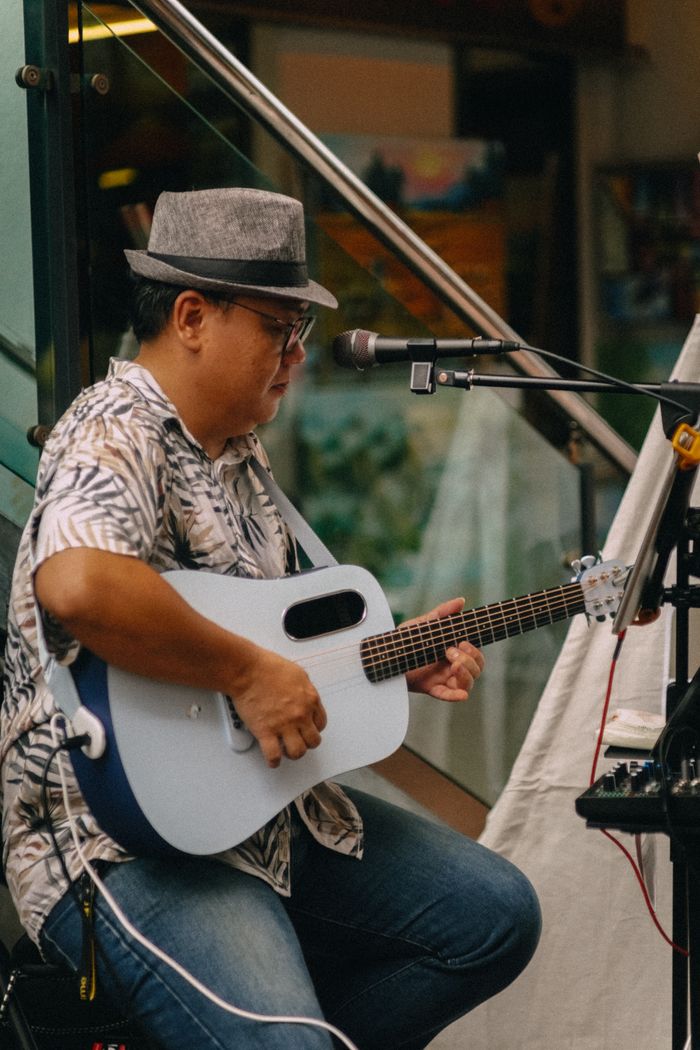 A musician strumming an acoustic guitar during an outdoor performance.