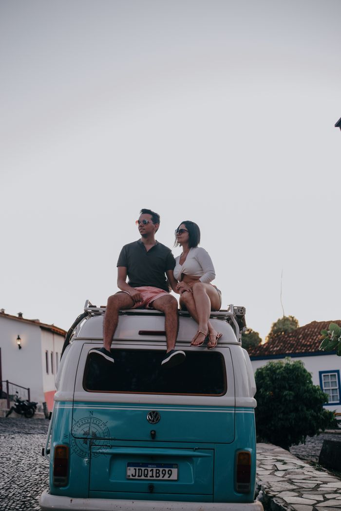 Couple sitting on a vintage van roof, enjoying a sunset with a relaxed vibe.