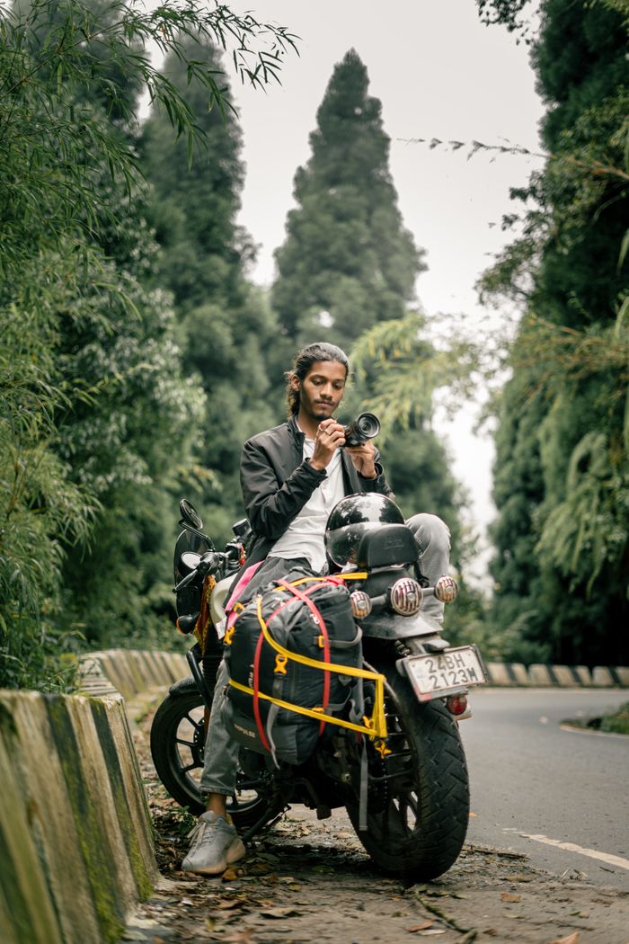 Young traveler on a motorcycle enjoying the lush greenery of Darjeeling's forests.